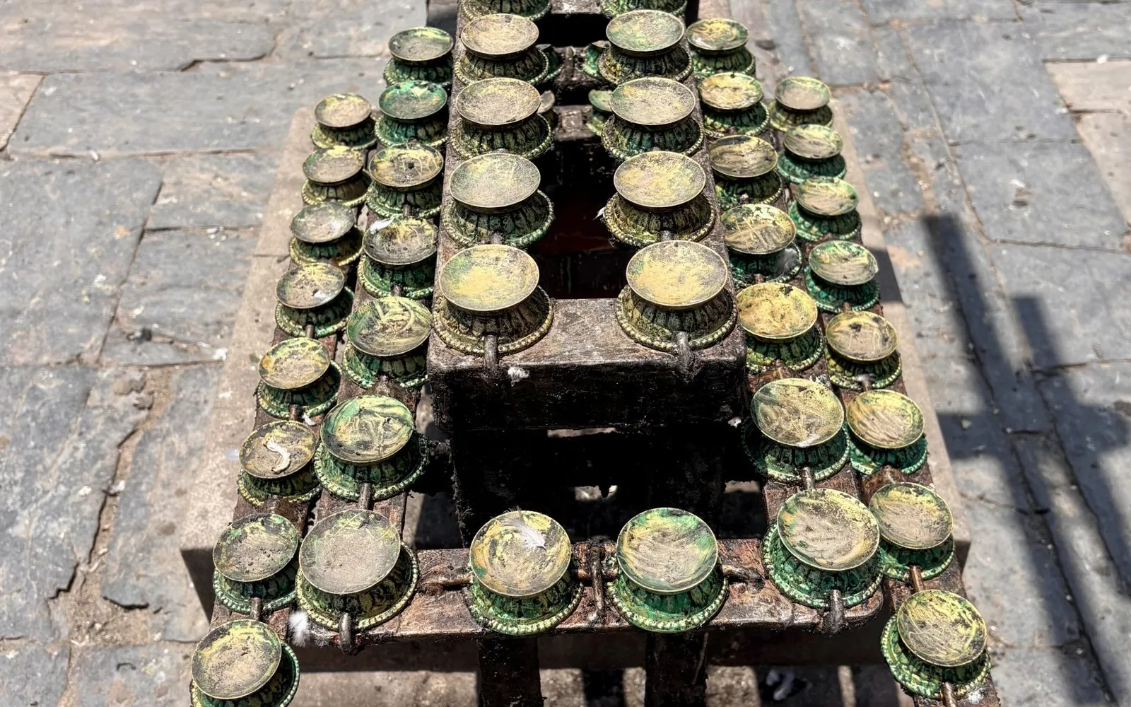 Rows of small brass oil lamps (diyas) arranged on tiered stands