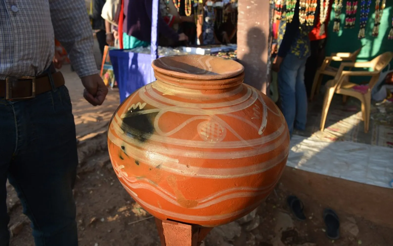 A decorated terracotta matka, the traditional clay drinking water pot, on a small stand at a market