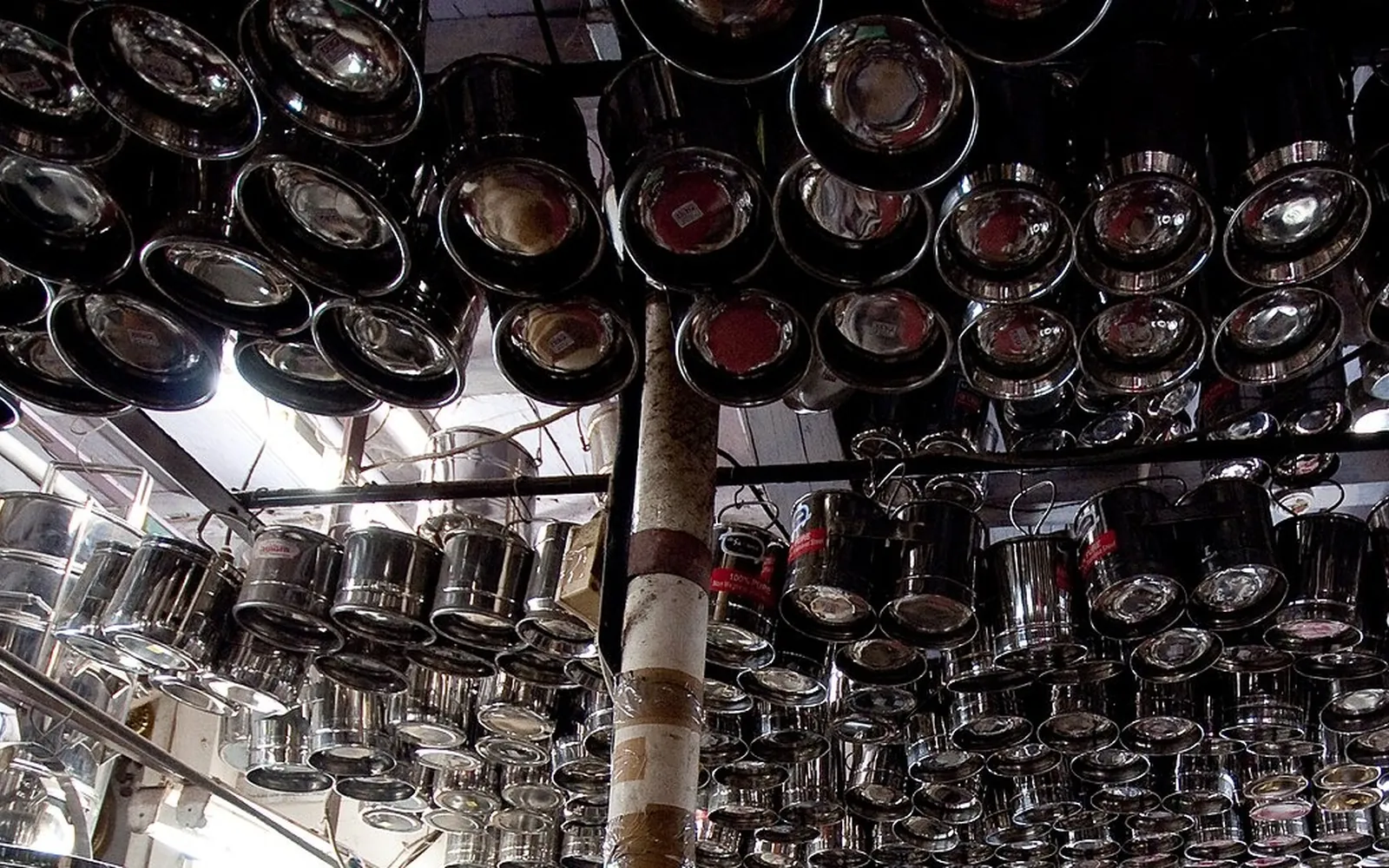 Hundreds of stainless steel pots, tiffin boxes and plates hanging from the ceiling of an Indian utensil shop