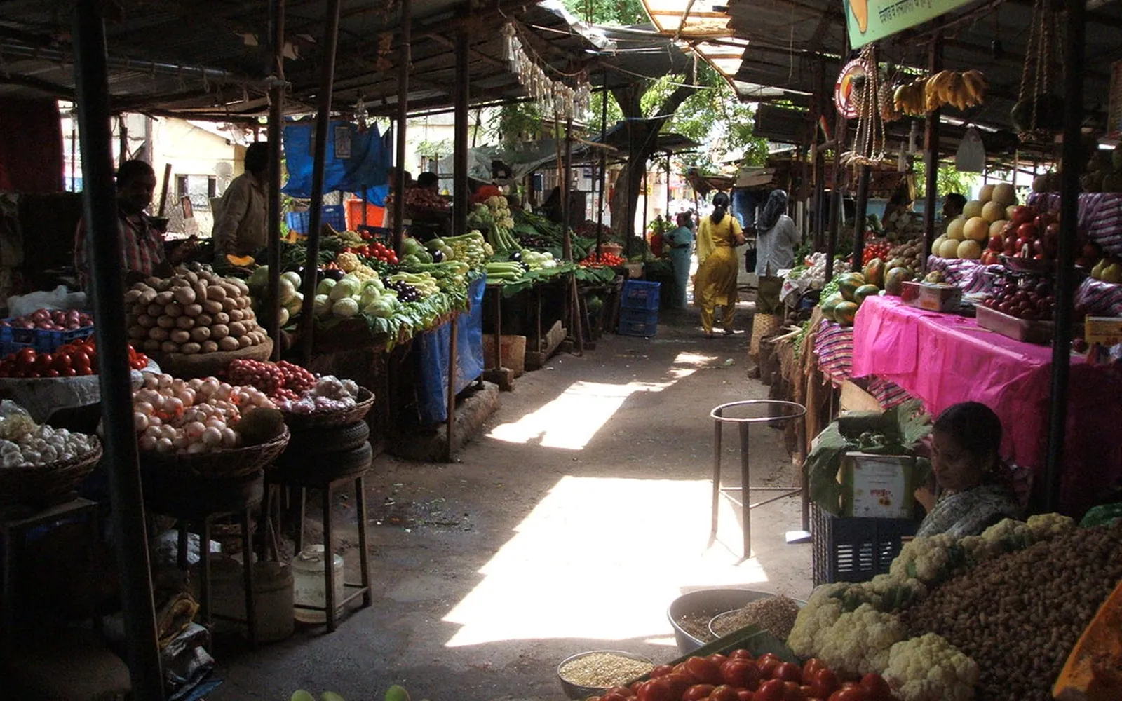 A covered Indian vegetable market with stalls of fresh produce